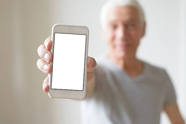 uomo anziano mostrando smartphone schermo - quizical foto e immagini stock