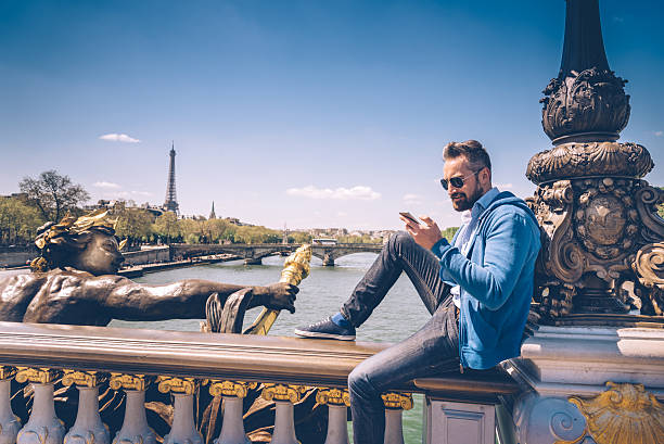 bearded man with mobile sitting on Pont Alexandre in paris