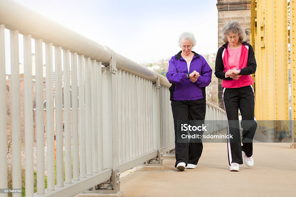 Women Checking Fitness Watches As They Walk A 73 year old woman and a 63 year old woman checking their fitness watches as they walk across a bridge to downtown Pittsburgh, Pennsylvania. Pedometer Stock Photo