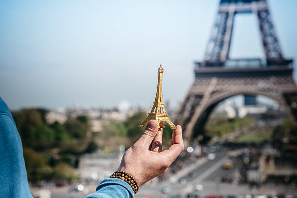 istock male hand holding  miniature tower in front of eiffel tower 527684292