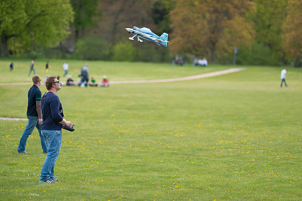 Gera, Germany - April 30, 2016: People with remote controllers at model aircraft show in Gera, Germany with one of the flying objects. At the open celebration called Hofwiesenparkfest, a lot of people show their work or hobby or sell goods. In the background some visitors walking trough the park