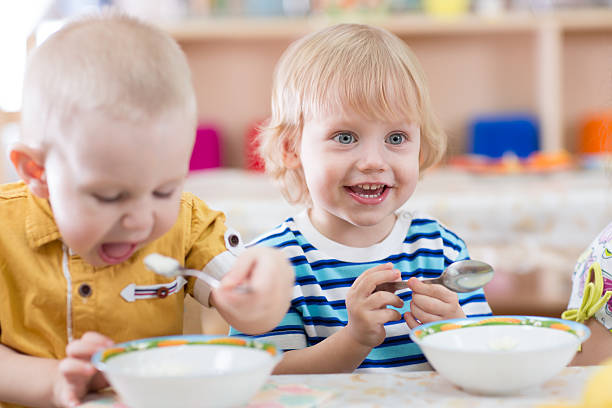 istock Funny smiling little kid eating in kindergarten 527687304
