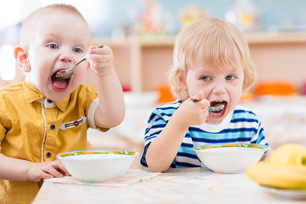 istock Funny little kids eating from plates in kindergarten 527687358