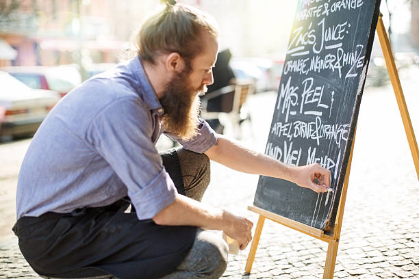 Cafe waiter writing todays special on the board Waiter writing todays special on the board outside the cafe real symbol stock pictures, royalty-free photos & images