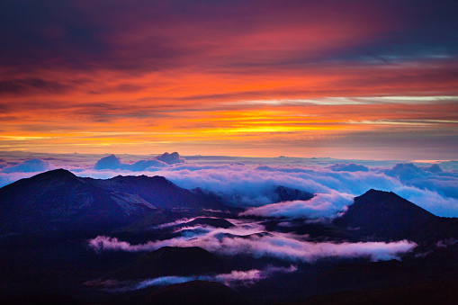 The sunrise in the Crater in Haleakala National Park  Maui, Hawaii. A volcanic crater on the peak of the Haleakala Volcano on top of the island of Maui. Over 10,000 feet above sea level, an incredible view from the crater at sunrise. A popular tourist destination all day, especially at sunrise and sunset. Photographed in horizontal format.