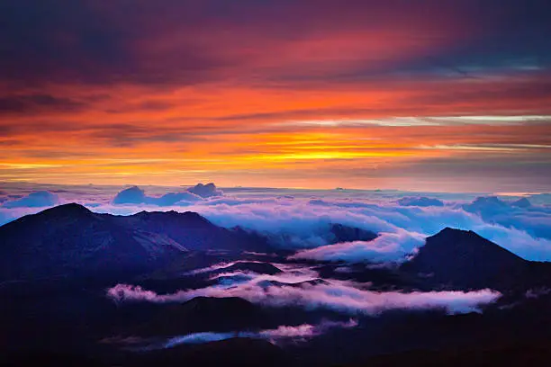 The sunrise in the Crater in Haleakala National Park  Maui, Hawaii. A volcanic crater on the peak of the Haleakala Volcano on top of the island of Maui. Over 10,000 feet above sea level, an incredible view from the crater at sunrise. A popular tourist destination all day, especially at sunrise and sunset. Photographed in horizontal format.