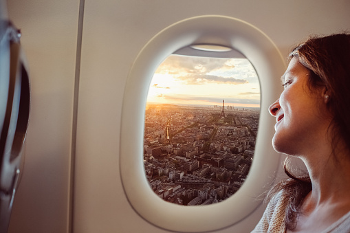 Smiling woman enjoying Paris from the airplane window