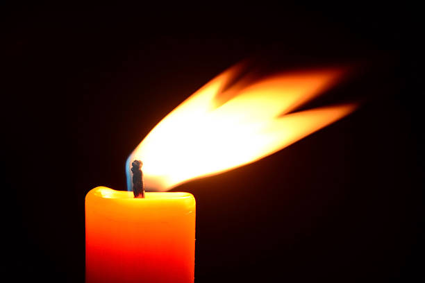 istock Orange candle burning on a black background 527690715