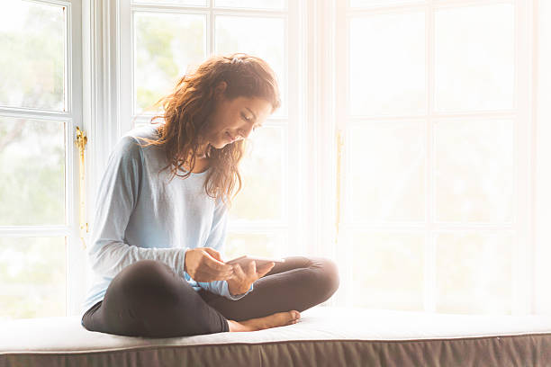 istock Young woman using digital tablet on window sill 527691404