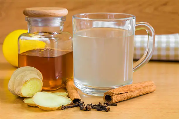 ginger tea with all the ingredients like ginger itself, cloves, lemon, honey and cinamon