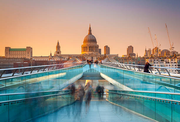 Busy commuters on their way home in London Blurred motion view over the Millennium footbridge looking towards St. Paul's Cathedral at sunset city of london stock pictures, royalty-free photos & images