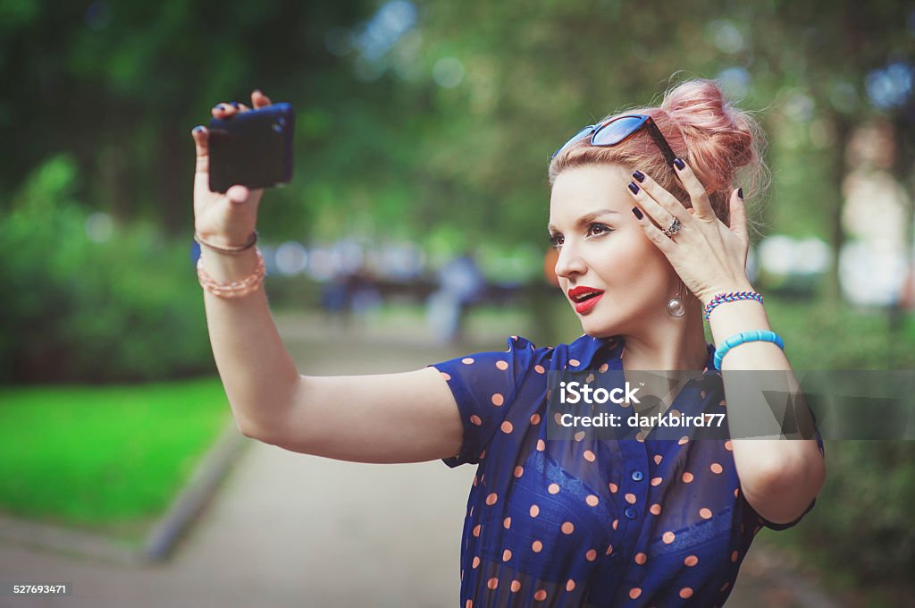 Beautiful young woman in fifties style taking picture of herself Beautiful young woman in fifties style taking picture of herself outdoor 1950-1959 Stock Photo