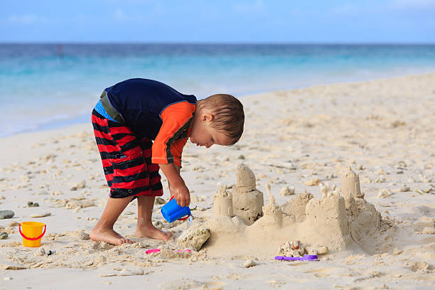 istock little boy building sand castle on beach 527696437
