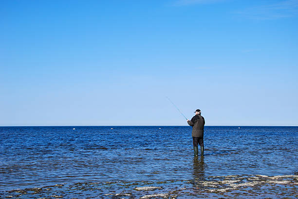 istock Man fishing at a flat rock coast 527696849
