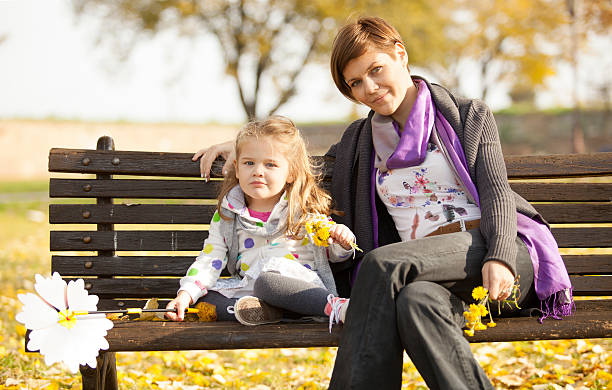 Mom And Daughter On Bench In Park - foto de stock