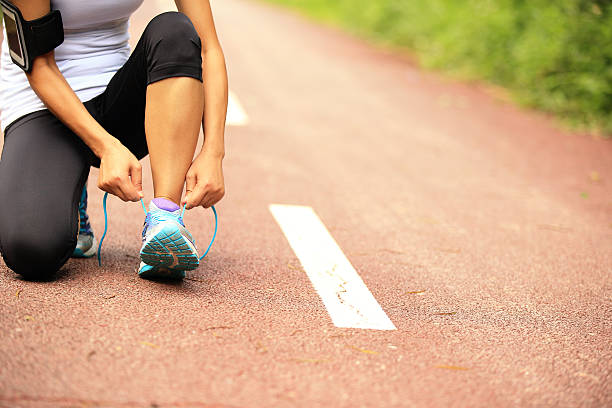 istock woman runner  tying shoelaces on trail 527704123