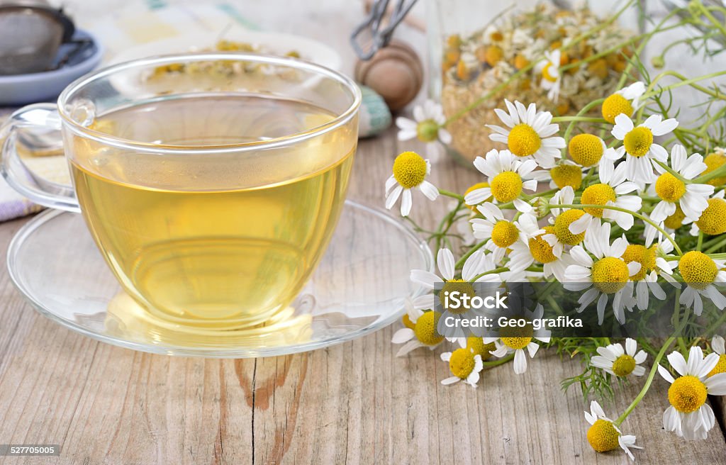 Cup of herbal chamomile tea. Cup of herbal chamomile tea on a wooden table. Chamomile tea in a transparent cup and camomile flowers on wooden table. Herbal tea for baby's stomach. Copyspace. Aromatherapy Stock Photo