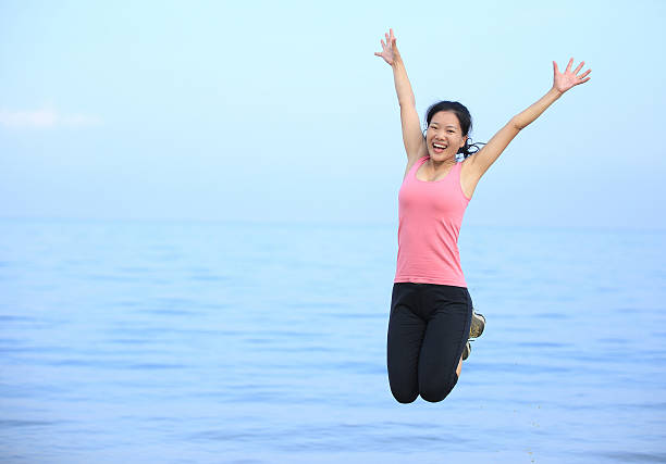 istock happy young asian woman jumping on beach 527706767