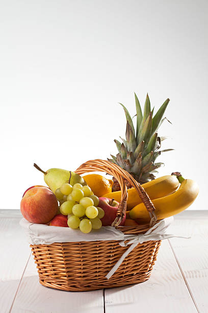 istock Fruit basket with pineapple, bananas, lemon, apple, peaches, grapes 527708269