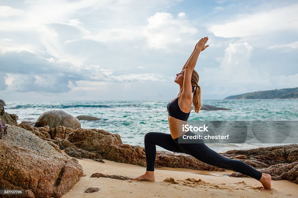 women doing yoga with the ocean behind  blond young women doing yoga with the ocean behind Adult Stock Photo