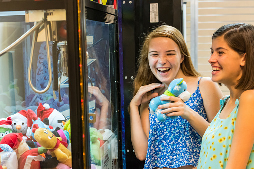 teenage girls having fun with a rag doll arcade machine