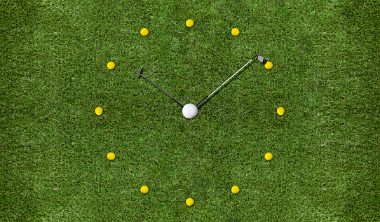 Clock shaped golf balls and clubs on green grass