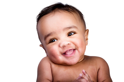 Cute little 6 month old baby boy of African and European Descent isolated on white.   He has no shirt on and is looking off camera making a funny face as if he's playing with someone.