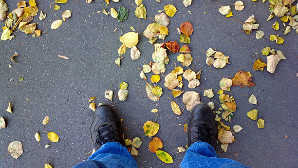 istock Feet on the asphalt with dry leaves. 527760281