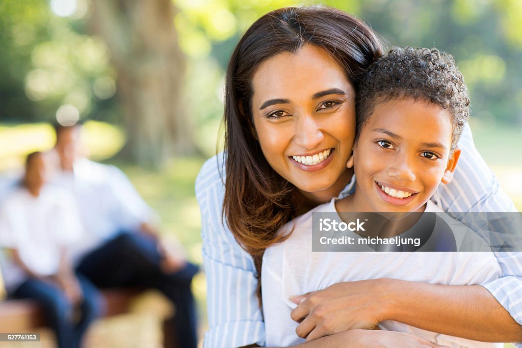 haapy indian mother hugging her son happy indian mother hugging her son in front of family outdoors Mother Stock Photo