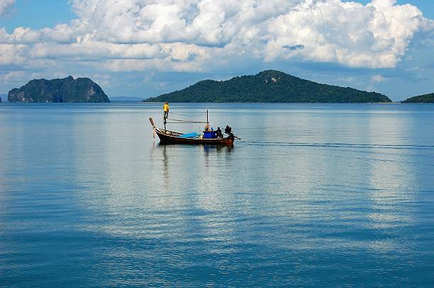 Koh Lanta, Thailand - November 22, 2013: Three Thai men on a long tail in the middle of the beautiful Andaman Sea, off Koh Lanta, Krabi province.