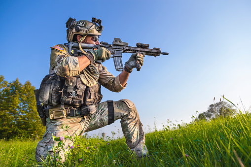 Portrait of American Soldier aiming his rifle on blue sky background