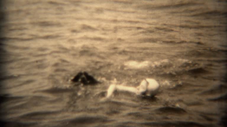 1936: Woman in swim cap and dog swimming together in open lake water.