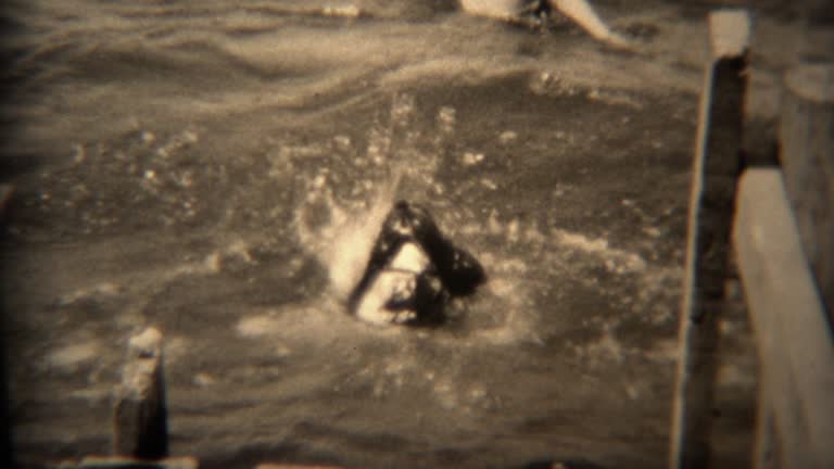 1936: Dog jumping off pier into lake water for a swim, regrets decision.