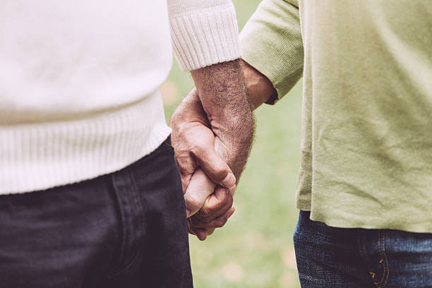 coppia gay mano nella mano al park - gay man homosexual couple homosexual men foto e immagini stock