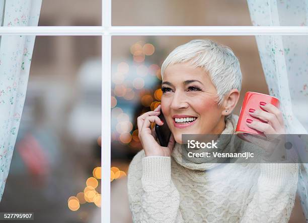 Schöne Lächelnd Reife Frau Blick Durchs Fenster Stockfoto und mehr Bilder von Winter - Winter, Frauen über 40, Alter Erwachsener
