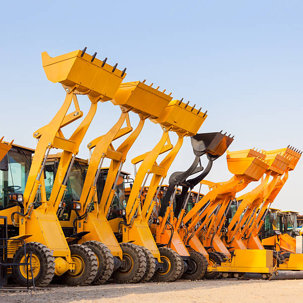 a linha de máquinas de construção pesada excavator contra azul sk - wheel tractor scraper imagens e fotografias de stock