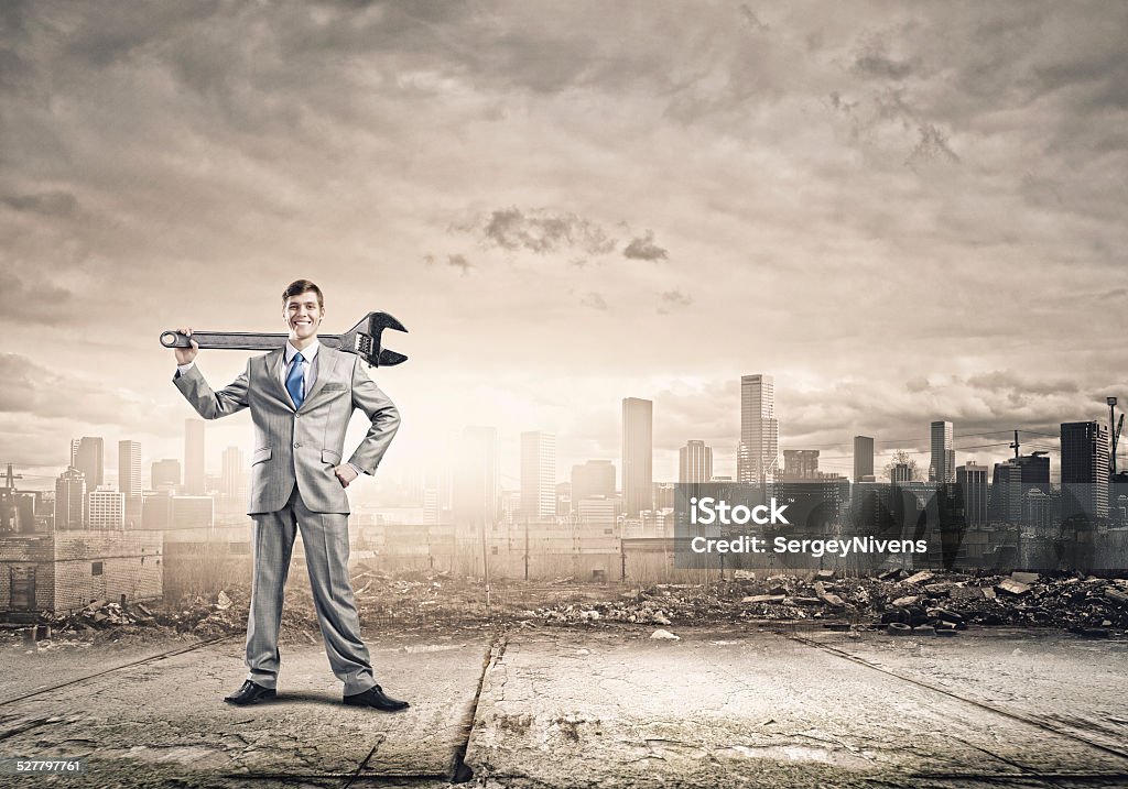 Working mechanism Young businessman with wrench against city background Achievement Stock Photo