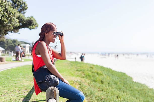 istock Tourist smiling while looking at the ocean through her binoculars 527813539