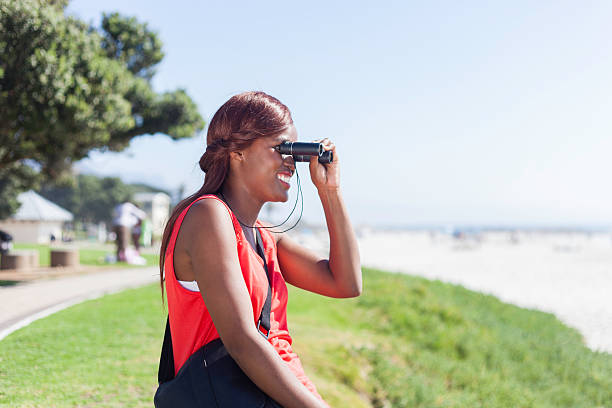 istock Tourist smiling while looking at the ocean through her binoculars 527813541
