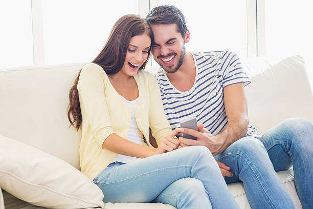 istock Cute couple relaxing on couch with smartphone 527819619