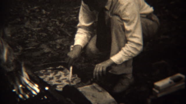 1937: Gourmet campfire cooking grilling pastries frying food.