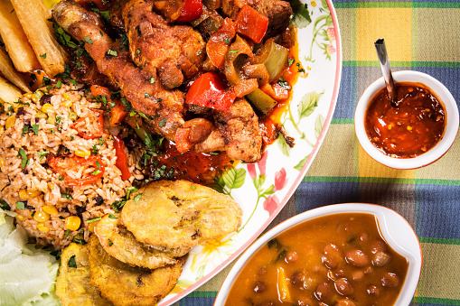 Stewed chicken with vegetables prepared in a typical Creole way served with rice, potato croquettes, beans and chili sauce.