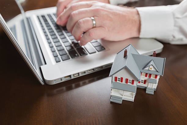 istock Miniature House Near Man Typing on Laptop Computer 527842855