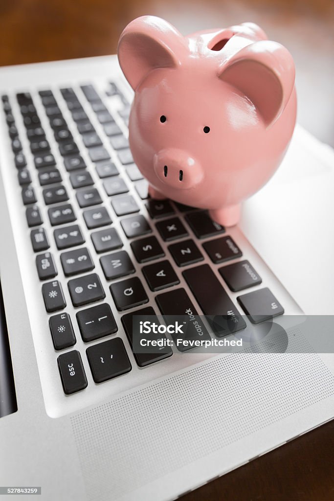 Piggy Bank Resting on Laptop Computer Piggy Bank Resting on Laptop Computer Keyboard. Banking Stock Photo