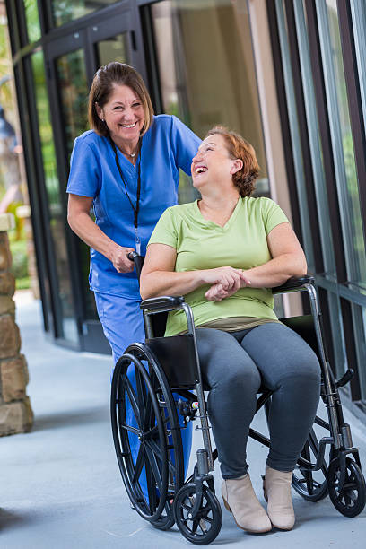 Happy nurse pushing patient in wheelchair after hospital discharge Happy nurse pushing patient in wheelchair after hospital discharge demobilization photos stock pictures, royalty-free photos & images