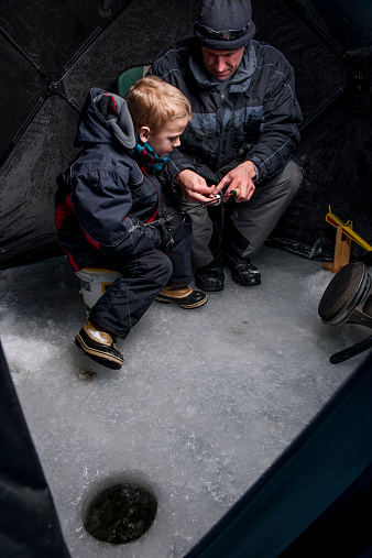 A father and son ice fishing together.