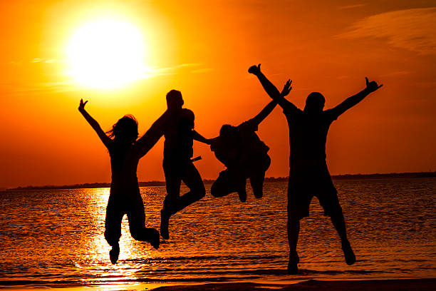 istock Spring break backlit group of young people jumping on beach 527857807