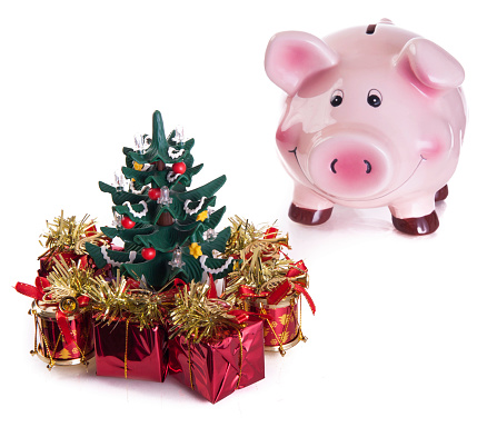 Happy pink piggy bank with gifts, front of christmas tree isolated on a white background