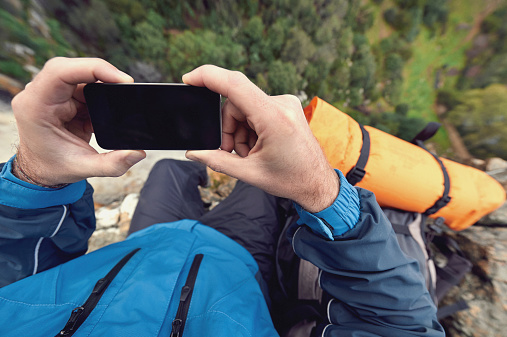 Adventure man with phone outdoors in wilderness exploring