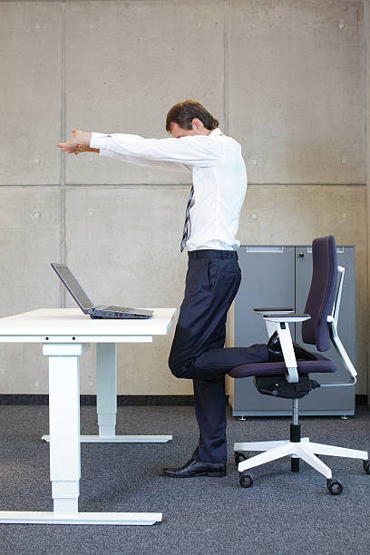 istock business man stretching in standing position at desk 527862679